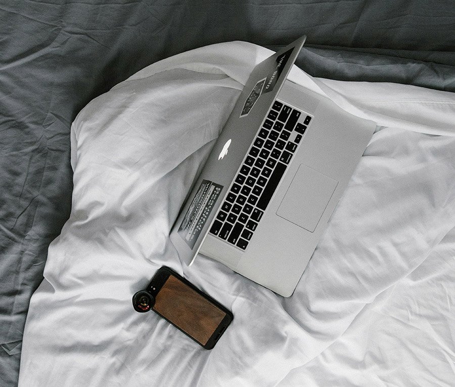 Laptop and smartphone on a bed